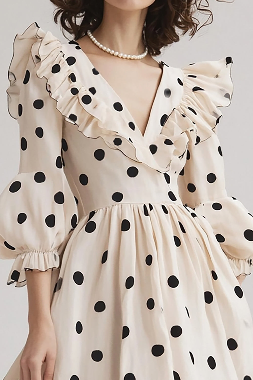 Robe en ivoire coupe A, col en V, à pois noirs volantés, avec manches bouffantes