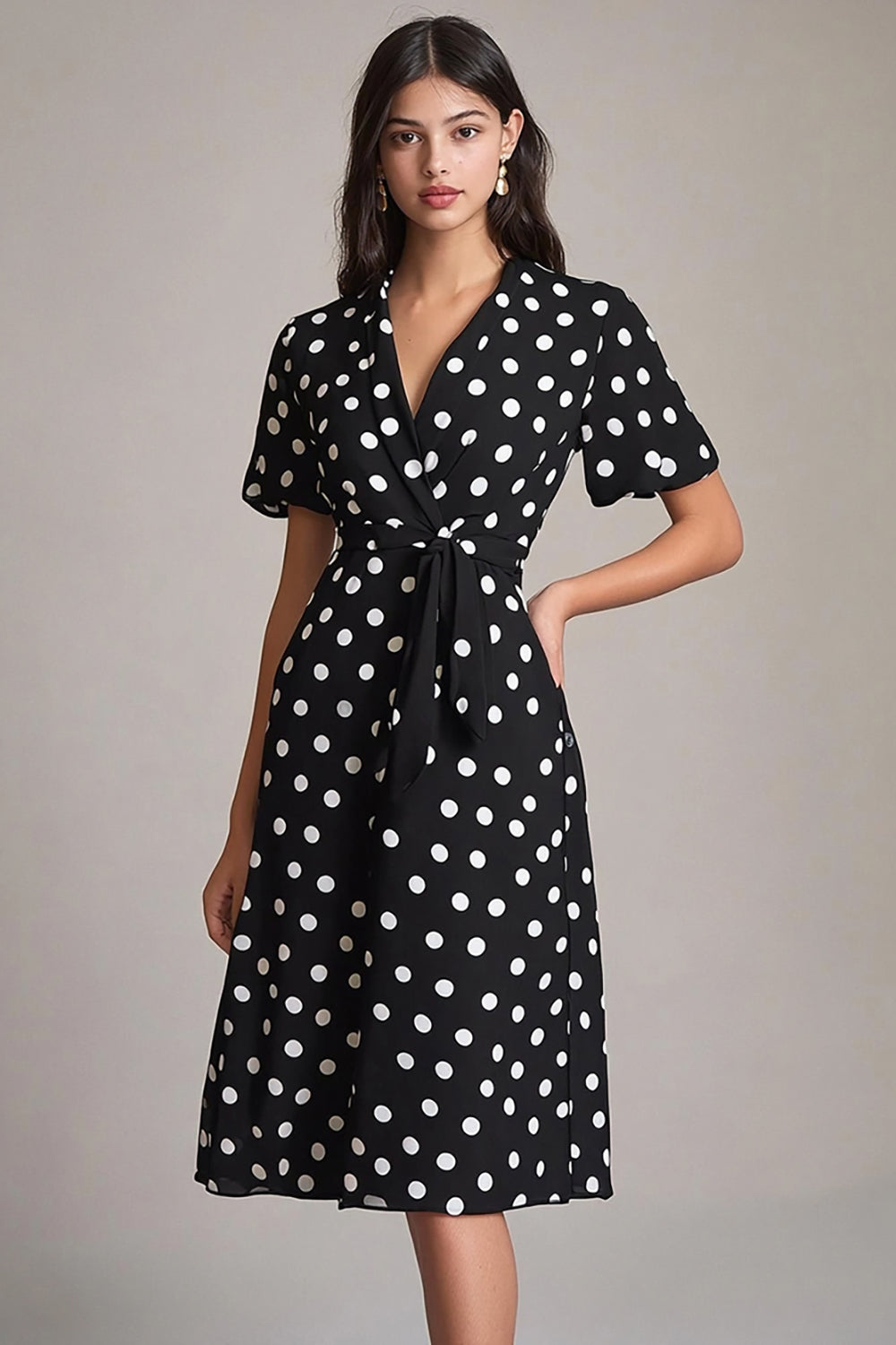 Robe à pois noire et blanche coupe trapèze avec décolleté en V et ceinture.