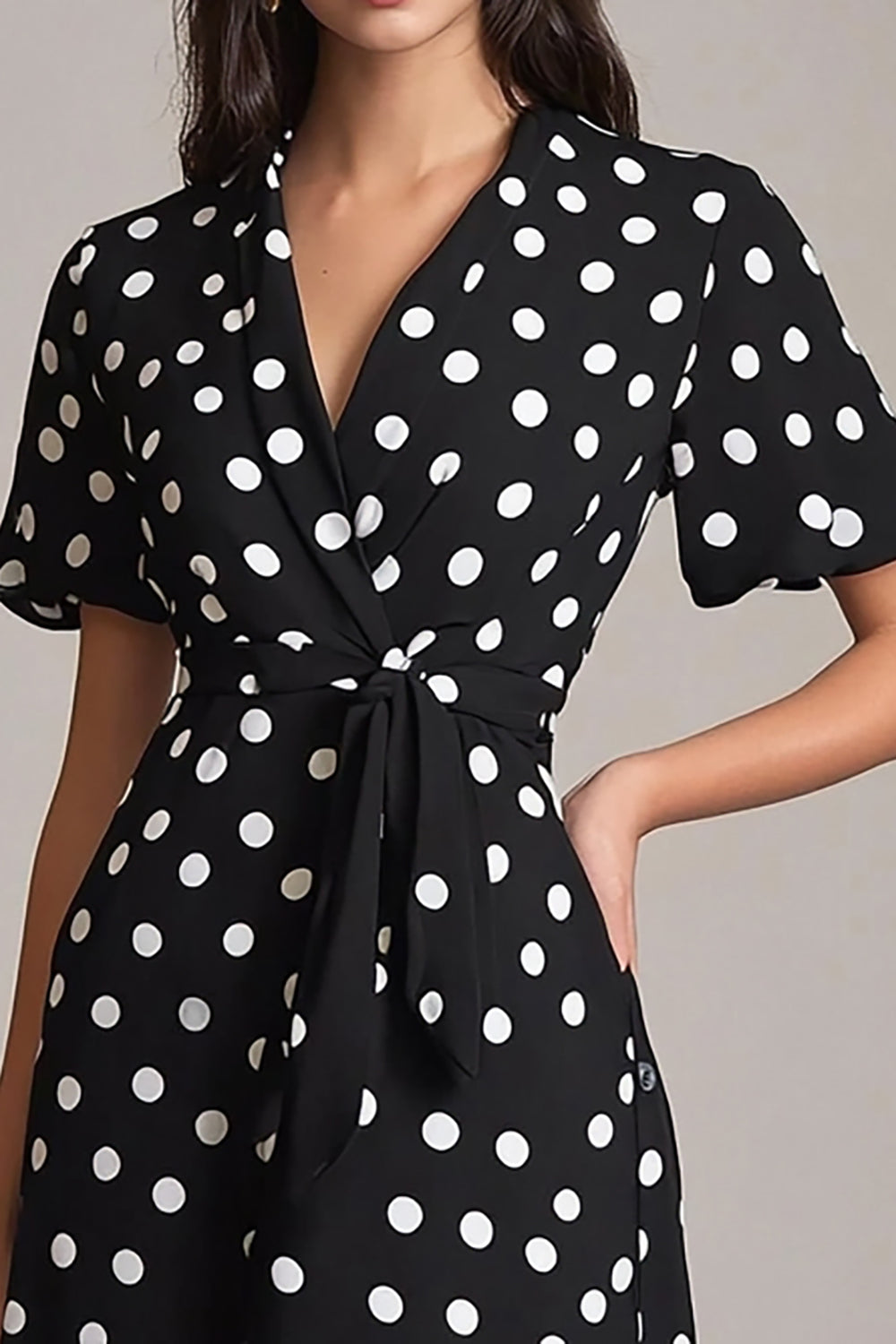 Robe à pois noire et blanche coupe trapèze avec décolleté en V et ceinture.