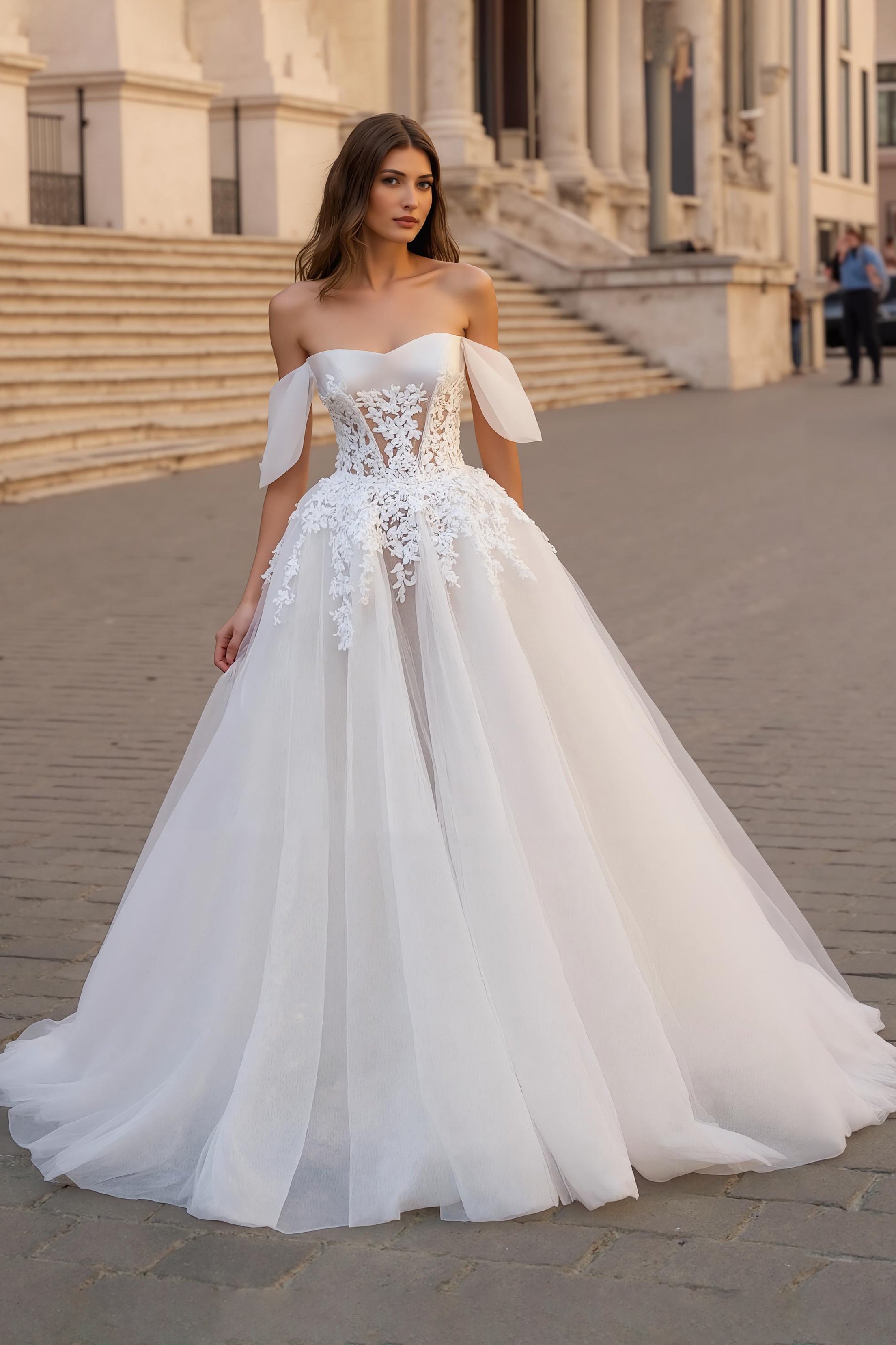 Robe de mariée ivoire avec des appliques, décolleté épaules dénudées, coupe trapèze et traîne.