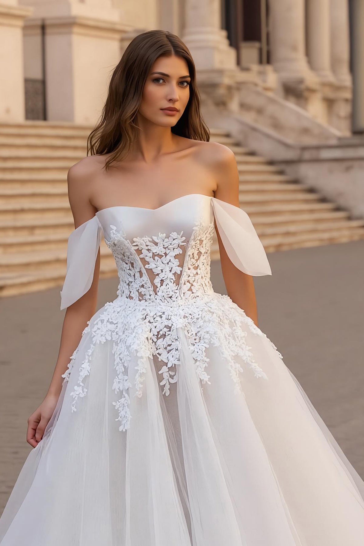 Robe de mariée ivoire avec des appliques, décolleté épaules dénudées, coupe trapèze et traîne.