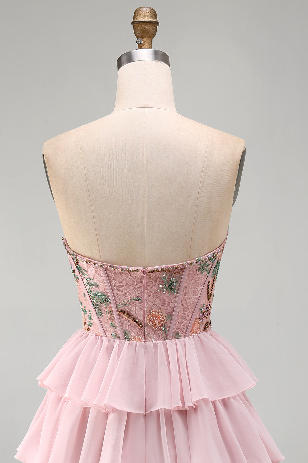 Robe de bal rose avec corsage bustier, taille basque, volants étagés et sequins