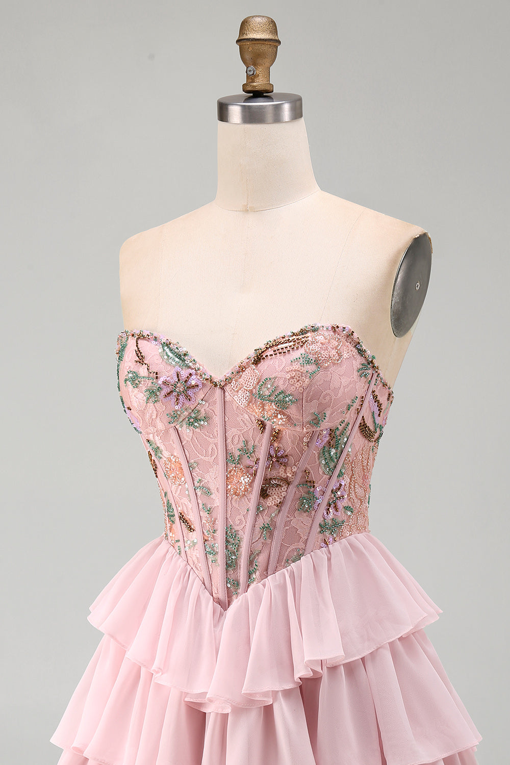 Robe de bal rose avec corsage bustier, taille basque, volants étagés et sequins